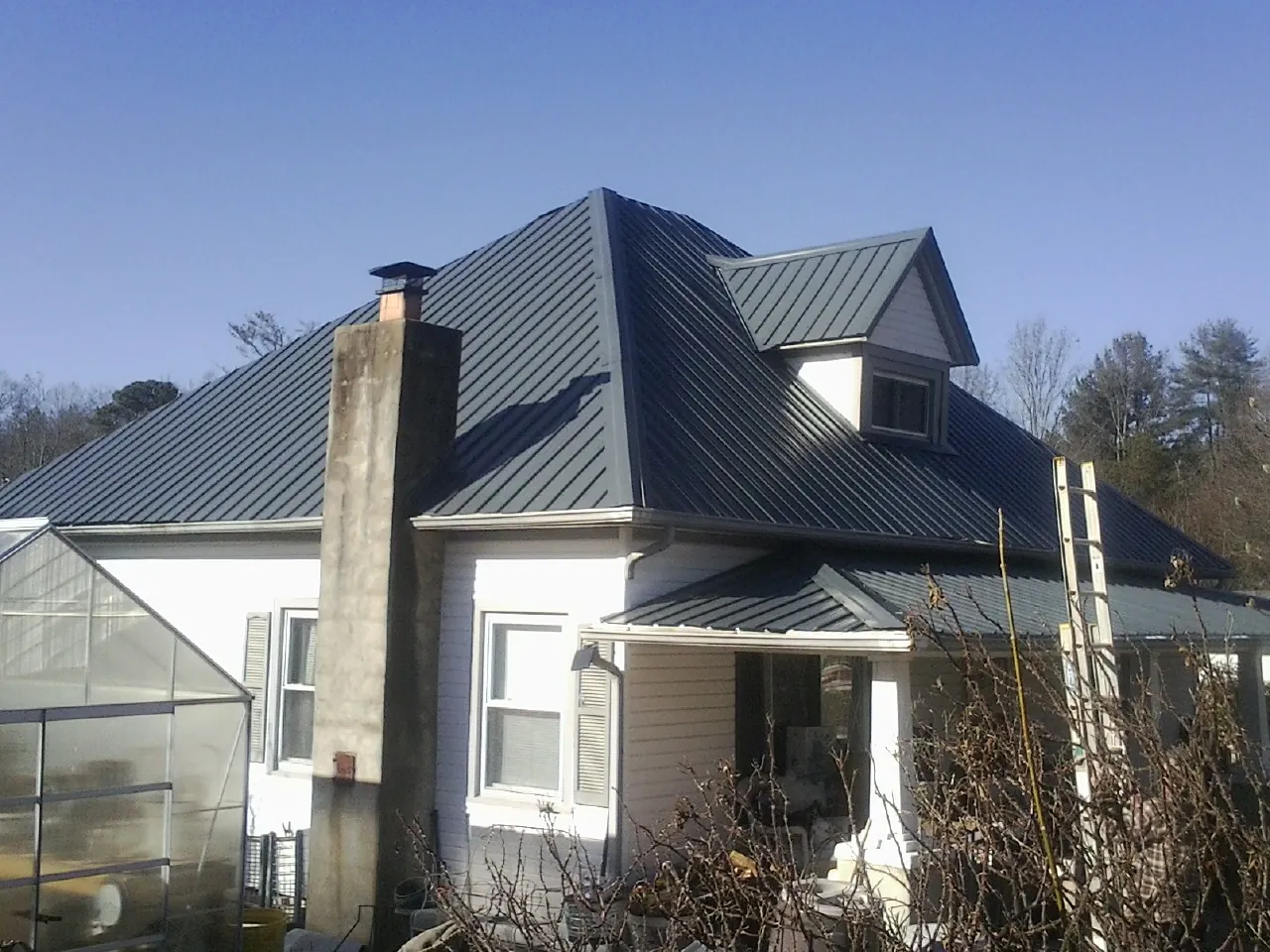 Dark blue standing seam metal roof on a white farmhouse with dormer — Slate & Tile Roof Repair by Roofing Brothers in Modesto