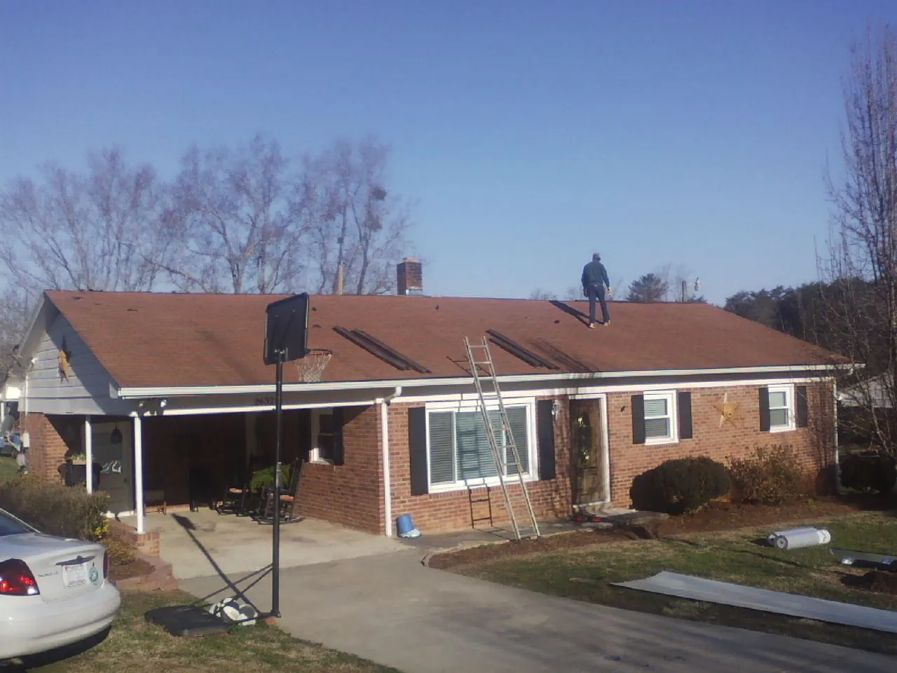 Roofer stripping a shingle roof on a brick ranch before metal panels in Modesto