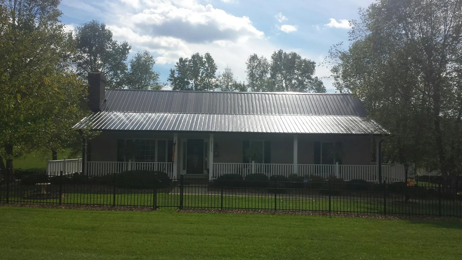Gray metal roof on a brick ranch with a full width front porch — Gutter Guard Installation work by our crew in Modesto
