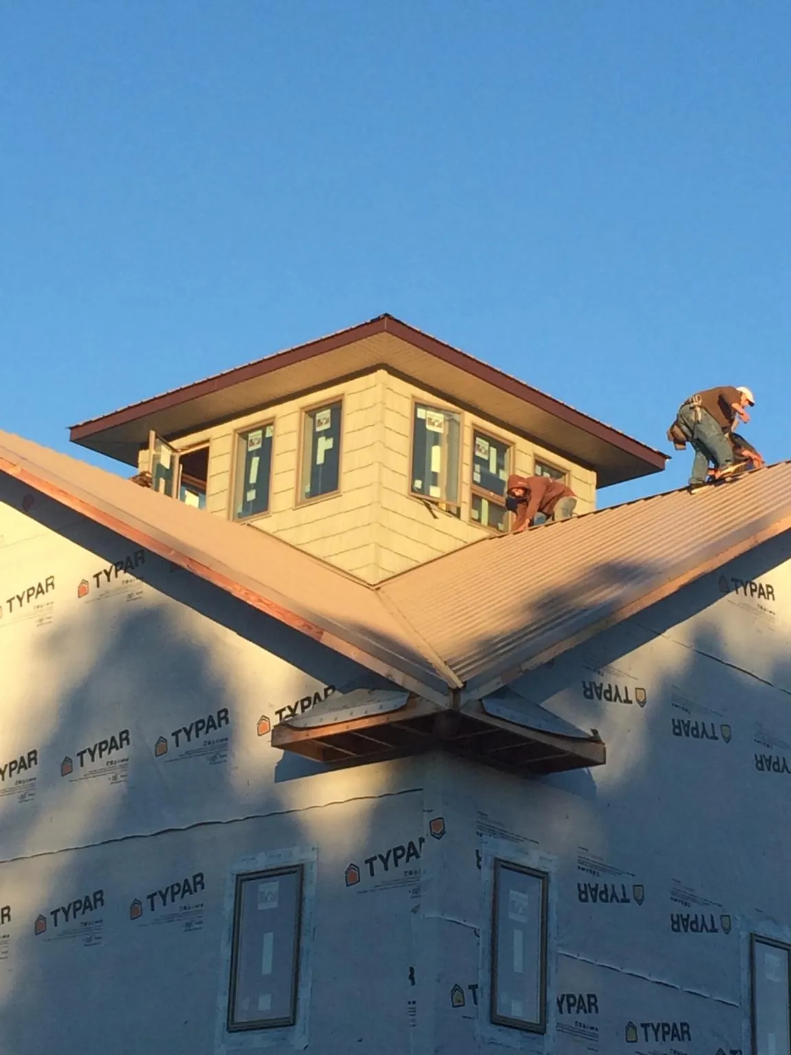 Roofers working around a rooftop cupola on a new metal roof at sunset — Roof Waterproofing in Modesto by Roofing Brothers